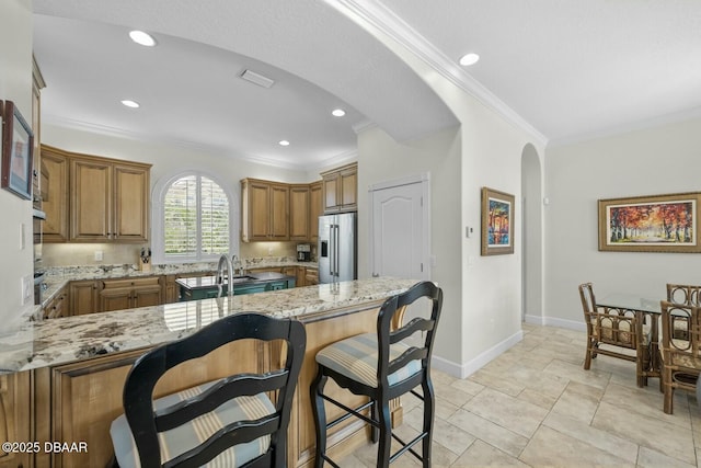 kitchen with crown molding, light stone countertops, high quality fridge, and kitchen peninsula