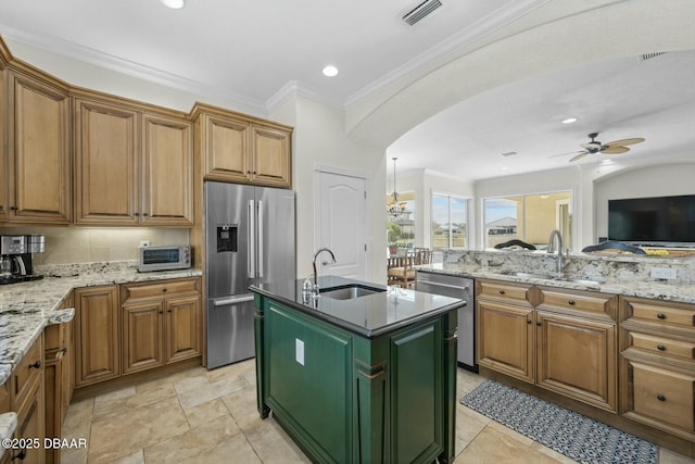 kitchen with sink, a center island with sink, ornamental molding, appliances with stainless steel finishes, and light stone countertops