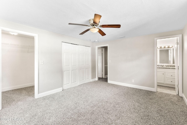 unfurnished bedroom with connected bathroom, ceiling fan, carpet floors, and a textured ceiling