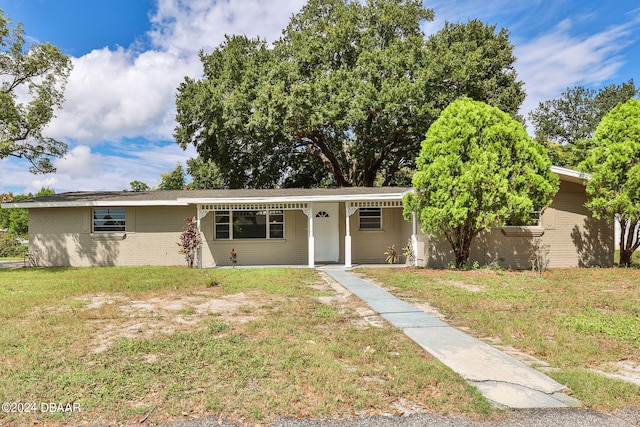 ranch-style home featuring covered porch and a front lawn