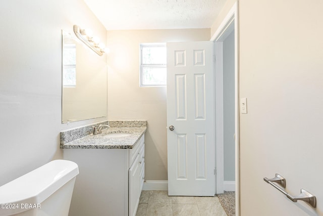 bathroom featuring a textured ceiling, vanity, toilet, and tile patterned floors