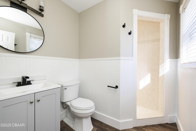 bathroom featuring a tile shower, vanity, toilet, and hardwood / wood-style floors