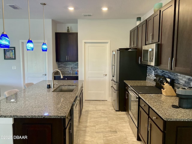 kitchen with appliances with stainless steel finishes, a sink, a kitchen island with sink, and dark brown cabinetry