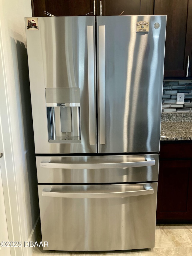 interior details featuring stone counters, backsplash, stainless steel refrigerator with ice dispenser, and dark brown cabinets