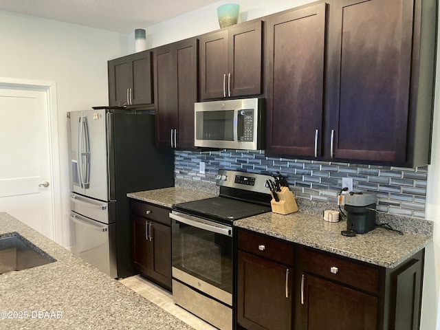 kitchen featuring light stone counters, appliances with stainless steel finishes, decorative backsplash, and dark brown cabinets