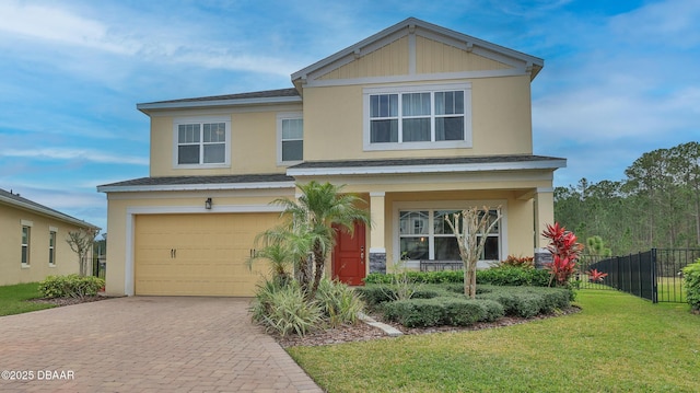 view of front facade with fence, a front yard, stucco siding, decorative driveway, and a garage