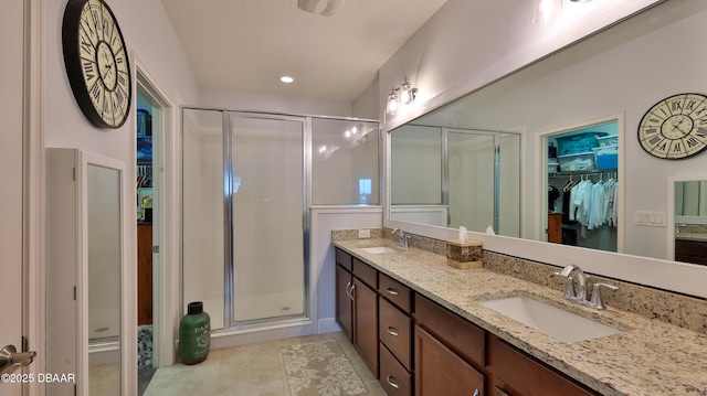 bathroom featuring a sink, double vanity, a stall shower, and a spacious closet