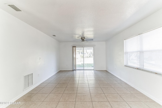 tiled empty room with ceiling fan and a textured ceiling