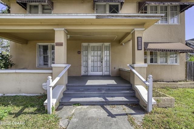 entrance to property with stucco siding and covered porch