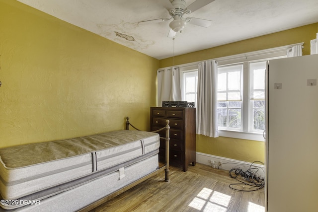 bedroom with a textured wall, a ceiling fan, and wood finished floors
