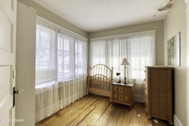 bedroom featuring baseboards, multiple windows, and hardwood / wood-style floors