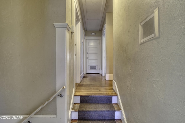 stairs featuring a textured wall, attic access, baseboards, wood finished floors, and visible vents