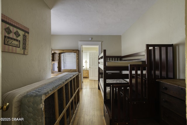 bedroom featuring a textured ceiling, a textured wall, and hardwood / wood-style floors