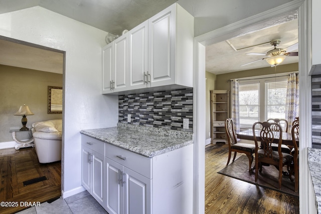kitchen with decorative backsplash, baseboards, ceiling fan, white cabinets, and dark wood finished floors