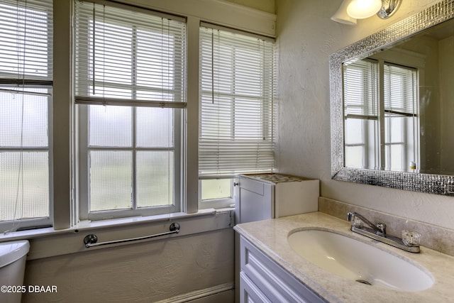 bathroom featuring a textured wall, a healthy amount of sunlight, and vanity