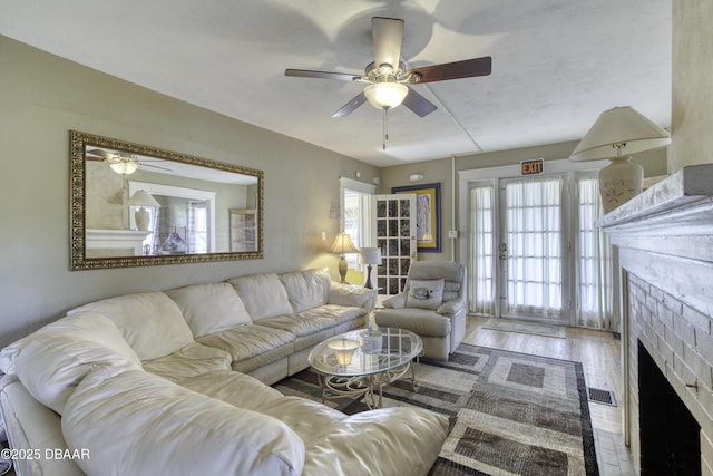 living area featuring ceiling fan, wood finished floors, and a fireplace