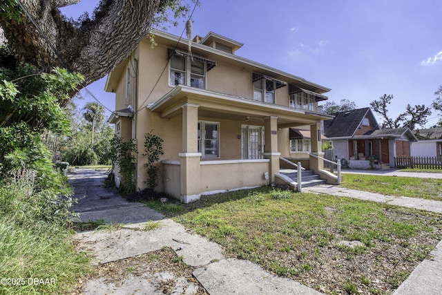 american foursquare style home with covered porch and stucco siding