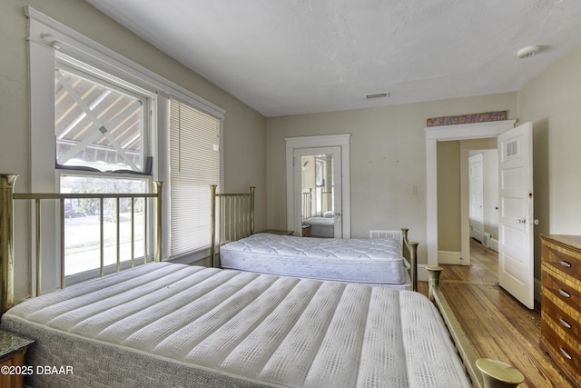 bedroom featuring baseboards, visible vents, and wood finished floors