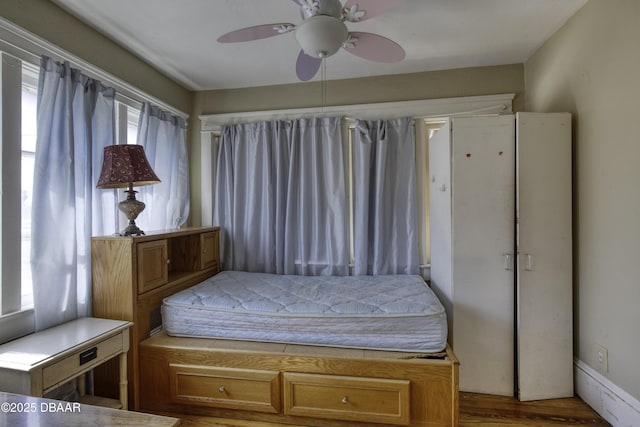 bedroom featuring multiple windows, ceiling fan, and wood finished floors