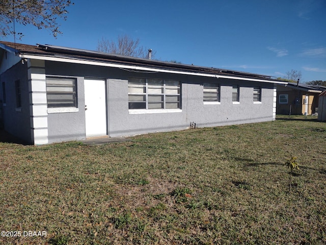 back of property with a lawn and stucco siding