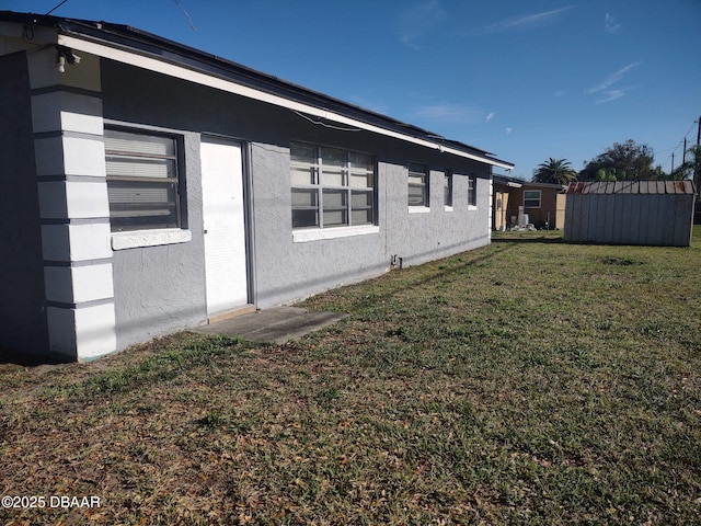 view of side of home featuring stucco siding and a lawn