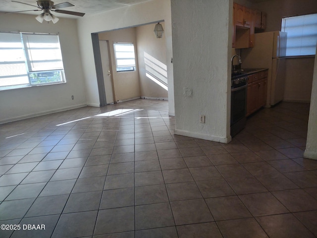 kitchen with gas stove, baseboards, ceiling fan, and tile patterned floors