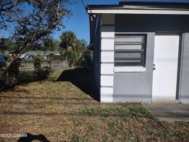 view of property exterior with stucco siding, a yard, and fence