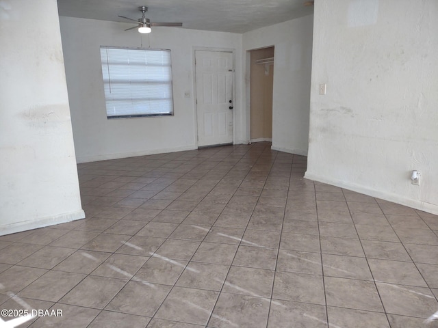 empty room with light tile patterned floors, baseboards, and a ceiling fan