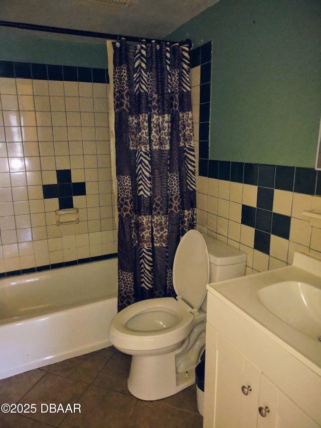 bathroom with vanity, shower / bath combo with shower curtain, tile patterned floors, toilet, and tile walls