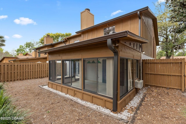 7 Appaloosa Trl, Ormond Beach, FL 32174 - rear view of house with a sunroom, a chimney, a fenced backyard, and board and batten siding