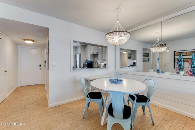 dining area featuring a chandelier, light hardwood / wood-style flooring, and sink