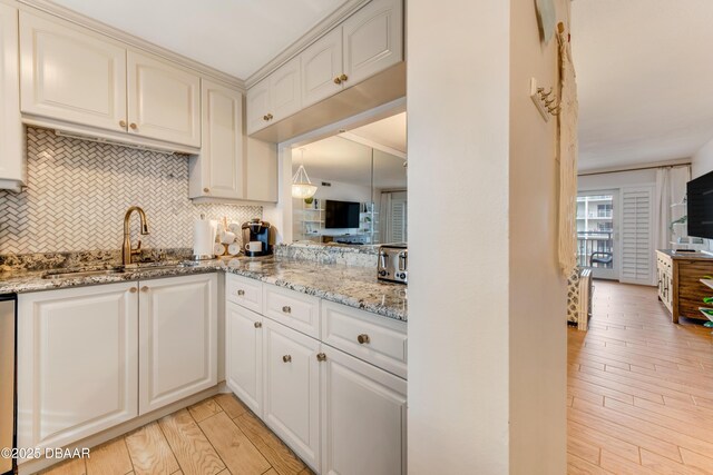 kitchen with light stone countertops, backsplash, light hardwood / wood-style floors, and sink