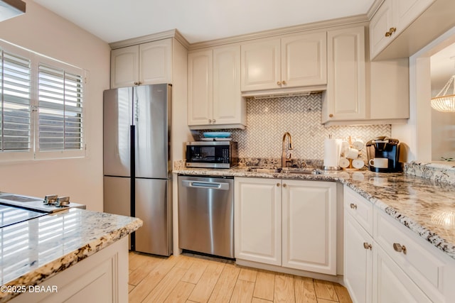 kitchen with cream cabinets, sink, appliances with stainless steel finishes, tasteful backsplash, and light stone counters