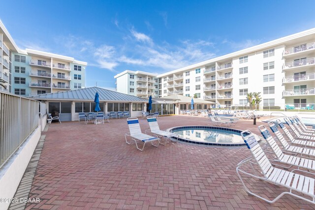 view of swimming pool featuring a hot tub and a patio area