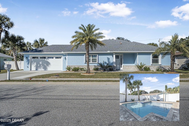 single story home with a garage, a pool with connected hot tub, fence, and driveway