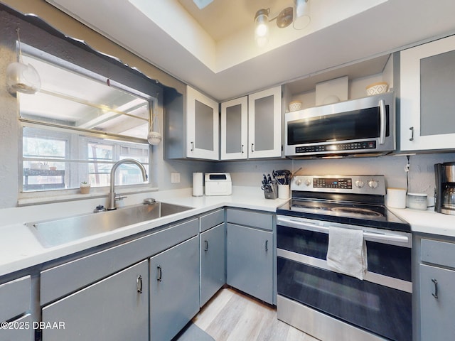 kitchen with light hardwood / wood-style floors, sink, gray cabinetry, and stainless steel appliances