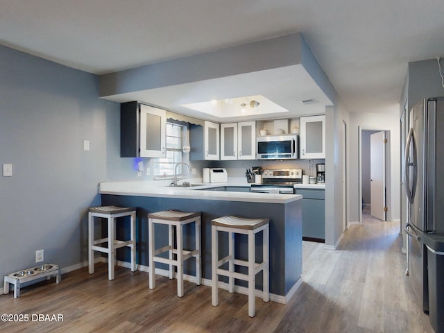 kitchen featuring white cabinets, light hardwood / wood-style flooring, kitchen peninsula, and appliances with stainless steel finishes