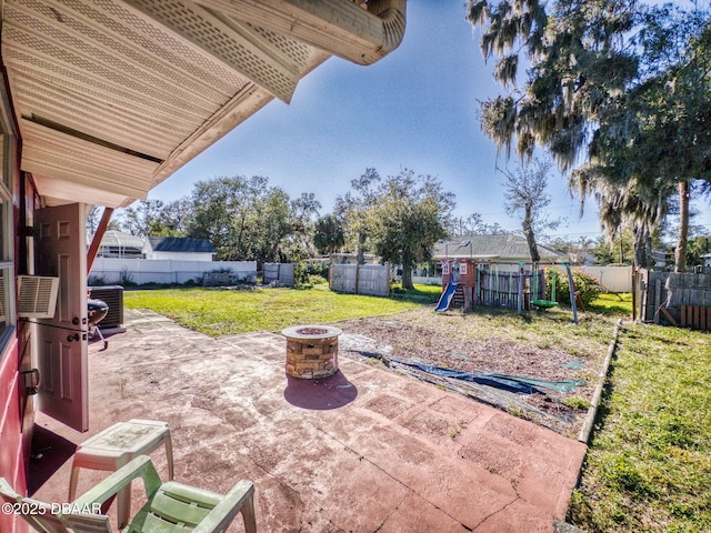 view of patio with an outdoor fire pit, cooling unit, and a playground