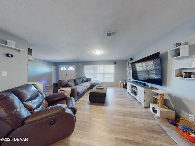 living room with light wood-type flooring and a textured ceiling