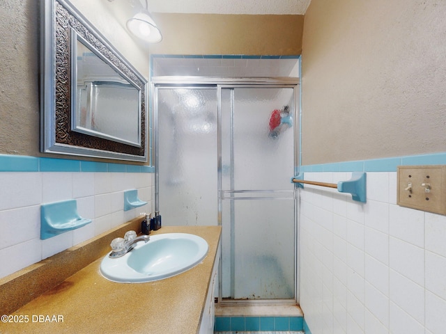 bathroom featuring vanity, walk in shower, and tile walls