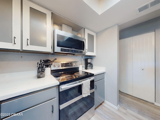 kitchen featuring stainless steel appliances, light hardwood / wood-style floors, and gray cabinetry