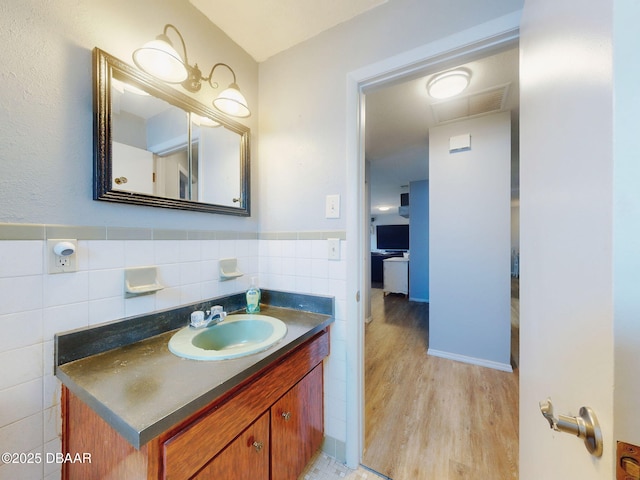 bathroom with hardwood / wood-style flooring, tile walls, and vanity