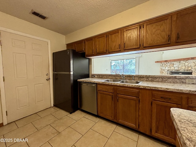 kitchen with a sink, visible vents, freestanding refrigerator, dishwasher, and brown cabinetry