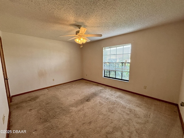 carpeted spare room with ceiling fan, a textured ceiling, and baseboards