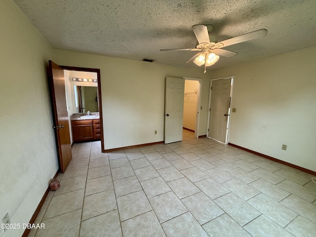 unfurnished bedroom with visible vents, a sink, a textured ceiling, and baseboards