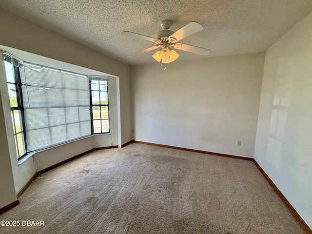 carpeted spare room with ceiling fan, baseboards, and a textured ceiling