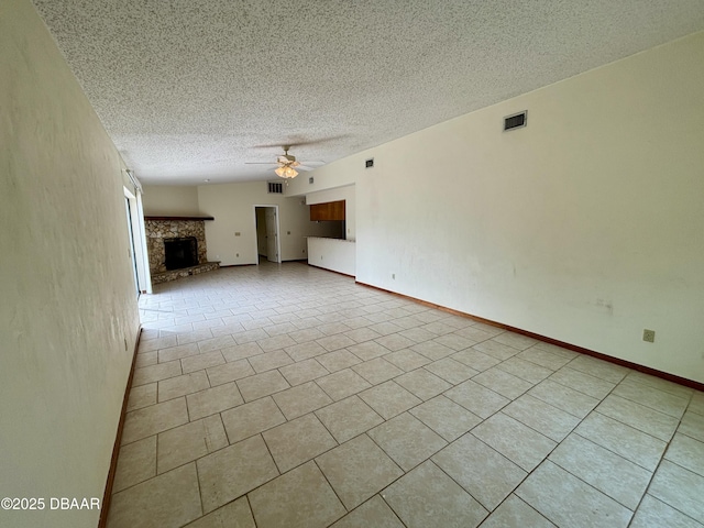 unfurnished living room with a fireplace with raised hearth, ceiling fan, a textured ceiling, visible vents, and baseboards