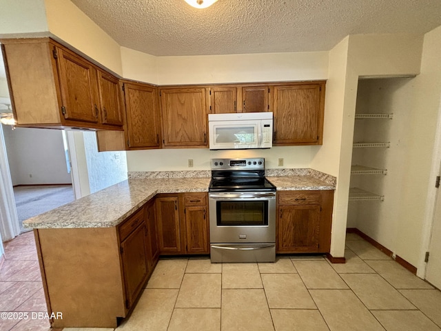 156 Riverwalk Ct, Ormond Beach, FL 32176 - kitchen featuring stainless steel range with electric stovetop, light countertops, white microwave, and brown cabinetry