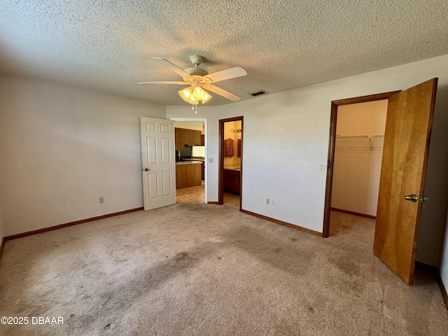 unfurnished bedroom featuring visible vents, baseboards, a closet, carpet, and a walk in closet