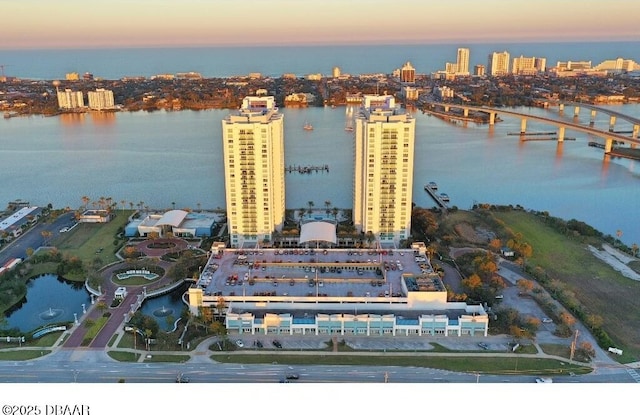 aerial view at dusk featuring a water view